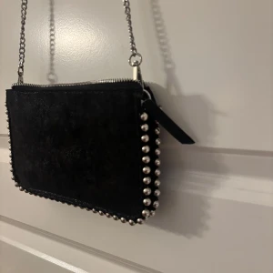 Svart axelväska med kedja och nitar - Super Snygg svart axelväska i mocka💕 Den är i väldigt bra skick då den endast är använd fåtal gånger!!