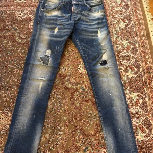 Blå jeans från Dsquared2 - Säljer ett par blå jeans från Dsquared2 med slitna detaljer och hål för en cool look. Jeansen har en skinny passform och är tillverkade i Italien. Perfekta för dig som vill ha en edgy stil.