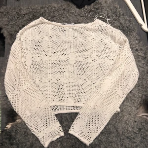 Vit spetsstickad tröja - Säljer en vit spetsstickad kroppad tröja med ett vackert mönster. Bra att ha på sig om man ska till stranden över sin bikini. 