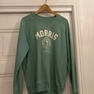 Grön sweatshirt från Morris - Säljer en grön sweatshirt från Morris med tryck framtill. Tröjan har långa ärmar och en rund halsringning. Perfekt för en avslappnad stil.