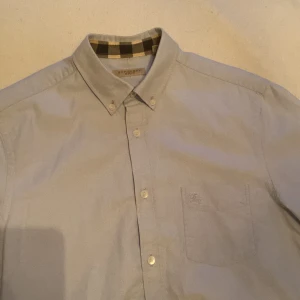 Ljusblå skjorta med rutigt foder - Snygg ljusblå skjorta från Burberry med klassiskt rutigt foder i kragen och ärmslut. Ny pris runt 3500kr 