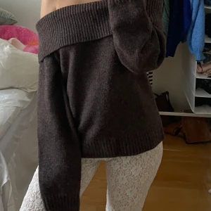 Brun offshoulder tröja - Säljer en mysig mörkbrun offshoulder tröja med långa ärmar. Perfekt för en avslappnad stil och kan enkelt matchas med olika outfits. Tröjan har en bred ribbad kant vid axlarna som ger en snygg detalj. Köpt för 800 för 3 månader sedan, aldrig använd!