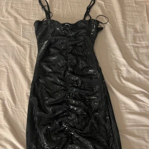 Svart glittrig klänning från Gina Tricot - Snygg svart klänning från Gina Tricot med glittriga paljetter och smala axelband. 
