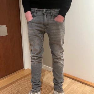 Grå jeans från Replay - Snygga grå jeans från Replay med en klassisk femficksdesign. De har en normal passform och är perfekta för en avslappnad stil. Jeansen har en dragkedja och knapp framtill. Han på bilden har storlek 28 i midjan och är en och 81cm lång. Jensen är andvända 3 gånger. 