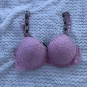 Rosa spets-BH från Victoria's Secret - Säljer en elegant rosa BH från Victoria's Secret med spetsdetaljer och glittrande axelband. Den har vadderade kupor och justerbara band för perfekt passform. Den har storlek 75C. Perfekt för att känna sig extra lyxig. Den är också push up. Priset kan också diskuteras ☺️