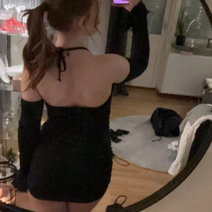 Svart klänning - Trendig svart klänning med tight passform. Klänningen har långa ärmar och en kort längd som ger en elegant look. Perfekt för en utekväll eller speciella tillfällen.