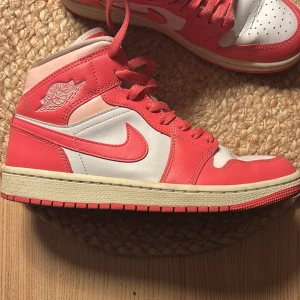 Nike Air Jordans i rosa och vit - Snygga Nike Air Jordans i en fräsch kombination av rosa och vitt. Skorna har klassisk snörning och den ikoniska Air Jordan-loggan på sidan. Perfekta för dig som vill ha en stilren och sportig look.