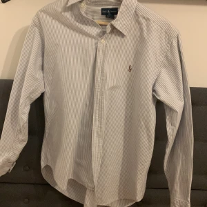 Ralph lauren skjorta  - En snygg vit och ljusblå skjorta från Ralph lauren i strl XS som endast är andvänd ett par gånger som också är i fint skick