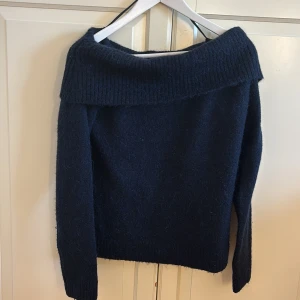 Mörkblå offshoulder tröja från Gina Tricot - Snygg mörkblå offshoulder tröja från Gina Tricot. Tröjan har långa ärmar och en bred ribbad kant vid axlarna som ger en stilren look. Perfekt för kyligare dagar. Andväbd två gånger så den är i ett jätte bra skick. Är i storlek 170 men passar en person som har storlek M eller S. 