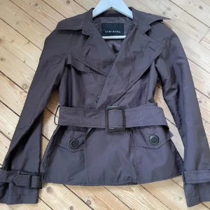 Brun trenchcoat från Zara  - Snygg brun trenchcoat från Zara med bälte i midjan och knappar framtill. Jättefint skick, endast använd fåtal gånger. Passar M bäst! 