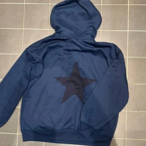 Mörkblå hoodie med stjärna - Säljer en unik mörkblå hoodie med en svart stjärna på ryggen!  Jätte skön, bra passform, skick 8/10🤝