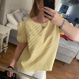 Gul blus med strukturmönster - Säljer en söt gul blus med korta ärmar och ett strukturmönster. Perfekt för vår och sommar. Blusen har en rund halsringning och en avslappnad passform🤩