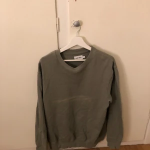 Grön tröja från East West - Säljer en stilren grön tröja från East West. Tröjan har en klassisk design med rund hals och långa ärmar. Perfekt för en avslappnad look.