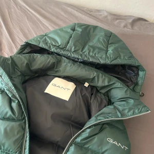 Gant Väst  - Skön och snygg Gant väst som är knappt använt då den är för stor, riktig snygg nu till våren, man kan även ta bort luvan.  Ny pris 2500kr