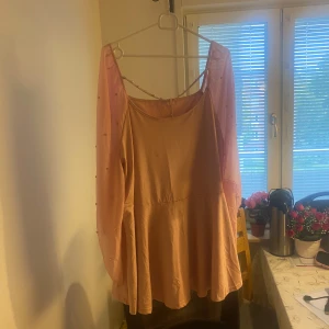 Rosa Blus - En rosa blus med genomskinliga ärmar och små pärlor. Blusen har en vid passform och en rund halsringning. Djur och rökfritt hem