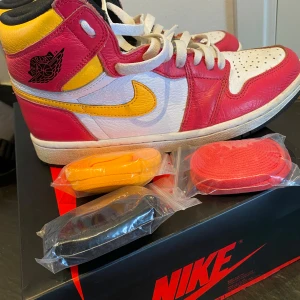 Air Jordan 1 Retro High OG Light Fusion Red - Säljer ett par sköna Jordan 1 fusion red. En oskadad box, tillsammans med 3 oanvända snören i olika färger kommer med. Nypris är 1300-3300, få för 999. De är i bra skick, med ett par små fläckar vid sidfoten (bild 5) som lätt går bort med en tvätt. 