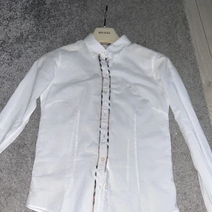 Burberry skjorta - Hej säljer nu min burberry skjorta för den e för liten men snygg stil ren skjorta ganska tunn storlek passar nog bra om du e mellan 154-161 liten knapp e av men lätt att sy en ny👍🏻🍾