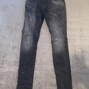Svarta super skinny jeans från Cars Jeans - Säljer ett par svarta super skinny jeans från Cars Jeans. De har en cool, sliten look med färgstänk och är i storlek 32/32. Perfekta för en avslappnad men stilren outfit. Passar bra till både vardag och fest!