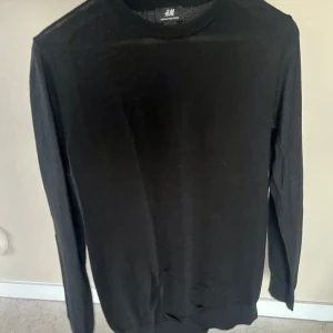 Svart tröja i merinoullblandning från H&M - Säljer en stilren svart tröja från H&M i en mjuk merinoullblandning. Perfekt för både vardag och fest. Tröjan har långa ärmar och en klassisk passform. Superbekväm och lätt att matcha med allt i garderoben! Skick: 7 av 10.
