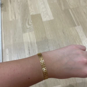 Guldarmband och örhängen i matchande design - Elegant guldarmband tillsammans med matchande örhängen. Armbandet har en fin, öppen design med små fyrkantiga länkar som ger en stilren look. Örhängena är små och diskreta, perfekta för både vardag och fest. 