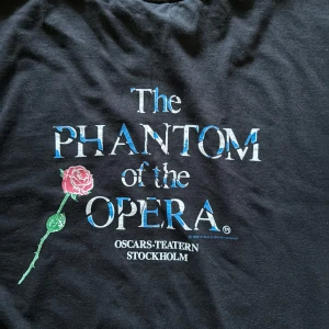 Svart t-shirt med Phantom of the Opera-tryck - Säljer en svart t-shirt tryck av Phantom of the Opera. Den visades mellan 1989-1994