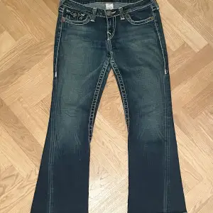 Made in USA vintage True Religion jeans. Mörkblå denim med vita sömmar. Bootcut och midwaist. Mått Midja ca. 41/82cm Inre benlängd ca.70cm Yttre benlängd ca.95cm Vidd nedtill ca. 23cm