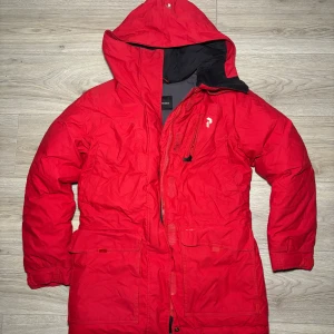 Peak - Röd Peak Performance vinterjacka i storlek s. Jackan har ett varmt, vadderat foder som håller dig varm under kalla vinterdagar.