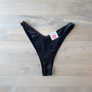 Svart glittrig bikiniunderdel - Säljer en helt ny superfin svart glittrig bikiniunderdel från Bik Bok. High leg modell. Perfekt för sommarens alla stranddagar! ✨