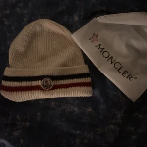 Moncler mössa  - Säljer min vita moncler mössa, hör av er för frågor. Köpte av min vän osäker på äktheten, därav priset!