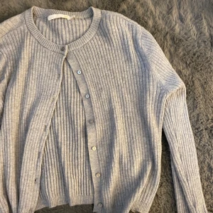 Grå ribbad kofta - Säljer en superfin grå ribbad kofta som är perfekt för kyliga dagar. Den har långa ärmar och knappar framtill, vilket gör den både stilren och praktisk. Passar perfekt till både vardag och lite finare tillfällen. 🩶 Nyskick