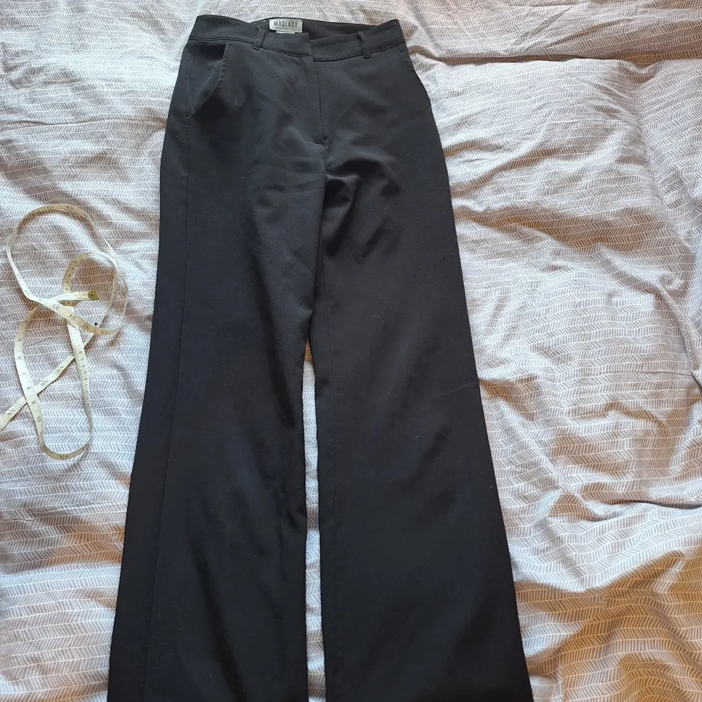 Svarta kostym byxor från Madlad i EU32 längden tall. Högmidjat. Lite nopriga men inga större defekter. 32 cm rakt över i midjan. Innerbens längd 84. Nypris 600. . Jeans & Byxor.