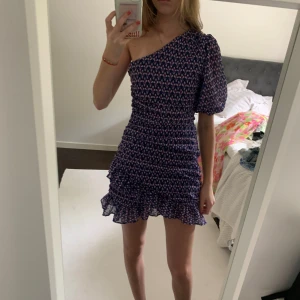 Mönstrad mörkblå klänning - Liten mörkblå mönstrad klänning med volang och en ärm, helt oanvänd med prislapp kvar, storlek S 💗Tryck inte på köp nu tack!