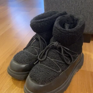 Svarta vinterkängor med teddyfoder - Säljer ett par svarta vinterkängor med mysigt teddyfoder. De har en robust sula med bra grepp och snörning framtill. Perfekta för kalla vinterdagar när du vill hålla fötterna varma och torra. Använda men i bra skick!