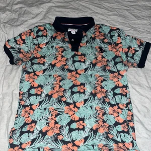 U.s. Polo Assn polotröja,storlek S - En snygg och färgglad polotröja med ett tropiskt mönster. Perfekt passar för vardagar eller fest
