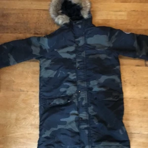 Camouflage parkajacka från JustHype - Säljer en snygg camouflage parkajacka från JustHype i storlek Small. Jackan har en mysig pälsfodrad huva och är perfekt för kalla dagar. Den har långa ärmar och stängs med dragkedja och knappar. Perfekt för vintern och hösten!