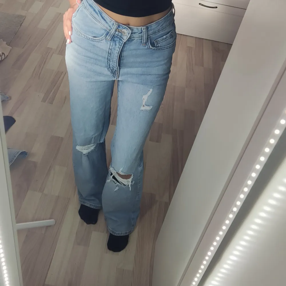 Säljer ett par ljusa jeans från Cubus i storlek XS. De är högmidjade och har en wide fit, vilket ger en skön och avslappnad look. Jeansen har coola slitningar på knäna som ger dem en trendig touch. Perfekta för både vardag och fest! . Jeans & Byxor.