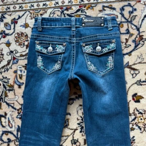 Fina bootcut jeans - Så fina bootcut jeans från rodeo girl med fina detaljer på fickorna Mått (cm) Midja ( tvärs över från de högsta kanterna) 31 Gren: 19 Innebenslängd: 73 Storlek 12 men stretchiga  Jag är 167 cm  Försmå så kan ej visa på. köpta för 650kr