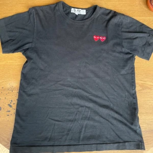 Svart Commes Des Carçons t-shirt - En stilren svart Cdg t-shirt som passar till det mesta. Väldigt skön och väldigt snygg. Använd en del men inte alls så det märks. Kvalitén skulle jag uppskatta till 7/10!