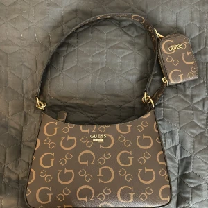 Guess axelväska till salu, bra skick, aldrig använt. - Guess brun och guld färgad väska, direkt från Dubai.