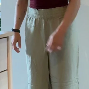 Beige linnebyxor med resårmidja - Säljer ett par bekväma och luftiga gröna linnebyxor. De har en hög midja med resår för extra komfort och en avslappnad passform. Perfekta för varma sommardagar eller en avslappnad stil. Byxorna är i bra skick och redo för en ny ägare!