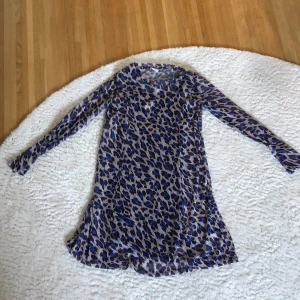 Leopardmönstrad, klänning med svart innerklänning. Lindex - Säljer en leopardmönstrad klänning med svart innerklänning, bandet på innerklänningnen har lossnat vid ena axeln, men går säkert lätt att sy fast.  Storlek 134/140