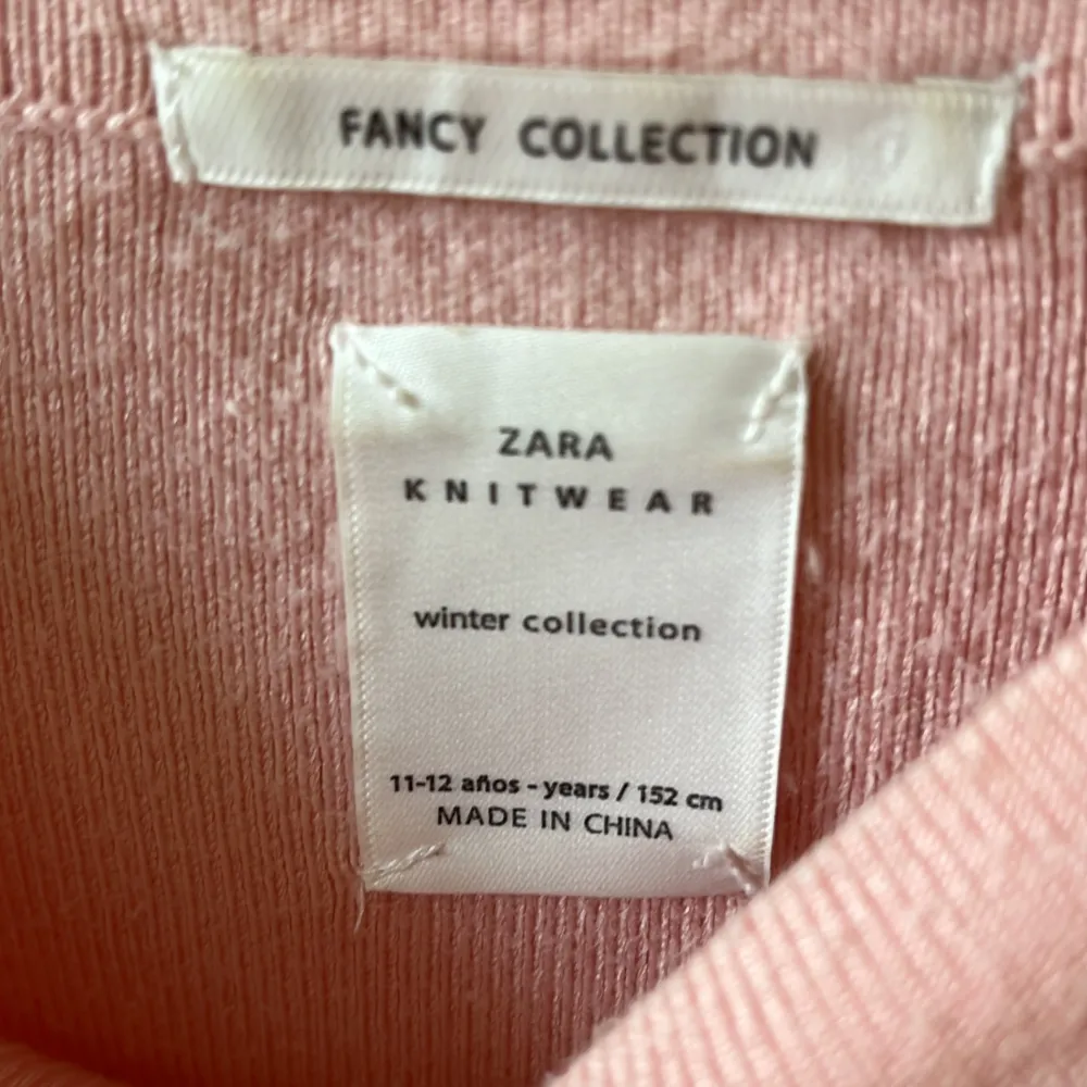 Säljer en superfin rosa stickad tröja från Zara, perfekt för vintern! Den är från deras Fancy Collection och har en söt svart rosett på varje sida vid ärmsluten. Tröjan är långärmad och gjord i ett mjukt material som håller dig varm och mysig. Passar perfekt till både vardag och festliga tillfällen!. Tröjor & Koftor.