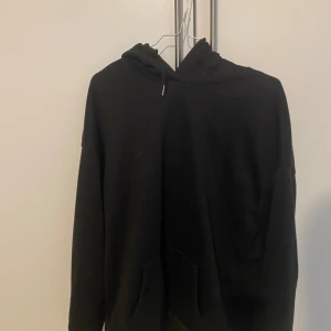 Svart hoodie med tryck - Säljer en svart hoodie med ett coolt tryck på baksidan. Trycket föreställer en staty med texten 'INTENSE FEELINGS' i vitt och rosa. Perfekt för en avslappnad stil och passar till alla tillfällen. Den har en klassisk passform med en skön huva och fickor framtill.