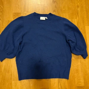 Blå stickad tröja från Vila - Säljer en snygg blå stickad tröja från Vila. Tröjan har puffiga ärmar och en rund halsringning. 