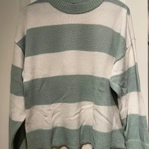 Randig stickad tröja från H&M - Säljer en mysig stickad tröja från H&M i grönt och vitt. Tröjan har breda ränder och långa ärmar, perfekt för kyligare dagar. Den är i storlek S och kommer från deras Divided-kollektion.
