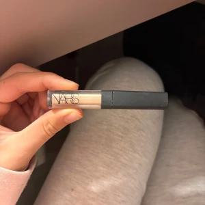 Concealer från NARS - Säljer en omvänd concealer från NARS i en ljus nyans. Perfekt för att täcka mörka ringar och ojämnheter. Kommer i en smidig tub med applikator för enkel applicering.