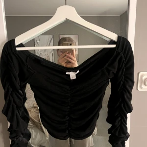 Svart långärmad topp från Amisu - Snygg svart topp från Amisu med långa ärmar och rynkdetaljer framtill. Perfekt för en stilren look. 