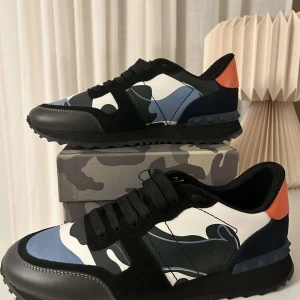 Valentino Rockrunner  - Snygga Valentino Rockrunner sneakers med kamouflagemönster i svart, blått och vitt. Skorna är bara använda ett fåtal gånger i början av hösten och har sen dess bara stått åt sidan. Kvitto finns som du kan se och har du andra frågor eller funderingar är det bara att säga till. Tack 