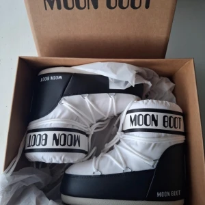 Vita och svarta Moon Boots - Säljer ett par vita och svarta Moon Boots med snörning. Perfekta för vintern. Har väldigt synliga tecken på användning speciellt på snörningen. Men är i väldigt bra skick, bärda två vintrar. Kan säkert tvättas för finare skick men aldrig testat! 