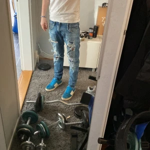  Replay jeans - Säljer ett par blå slitna jeans från Replay, modell Anbass. De har en slim fit passform och är dekorerade med flera slitningar för en trendig look. Perfekta för en avslappnad stil. 